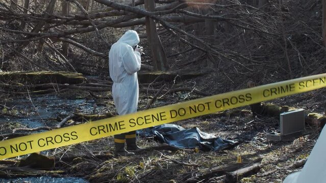 Forensic specialist working in the forest. Police criminalists collecting evidence and making criminal investigation. Crime scene concept.