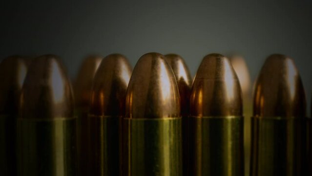 Gun Bullets Ammunition Close Up Ammo Zoom Out. Zoom out from a few gun bullets huddled together on a table. Tracking shot