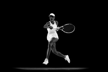 Dynamic photo of tennis player jumping to hit overhead shot in match against black studio...