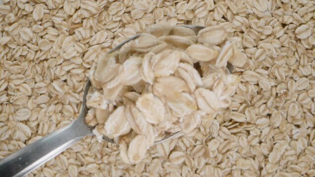 Top view of a spoon of oats against the background of rotating oat flakes. Focus technique shifts the image from the foreground to the background.