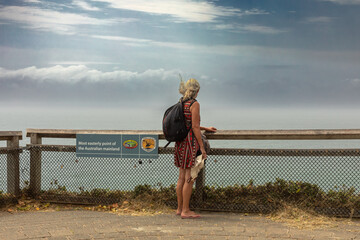 A woman, on a round-the-world adventure tour, looks out over the Pacific Ocean from Cape Byron, the...