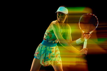 Young woman, tennis player with vibrant trail effect during backhand swing against black studio background Motion blur effect. Concept of sport, active lifestyles, tournaments, energy, movement.