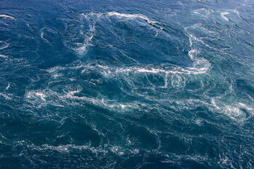 Close-up of the Saltstraumen maelstrom's intricate patterns, where deep blues and frothy whites...