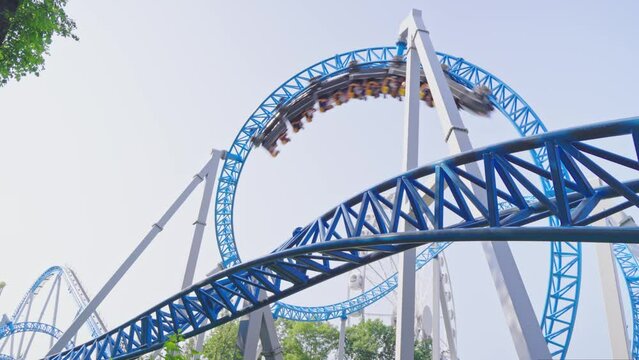 Roller coaster Ride against blue sky. Roller coaster in the amusement park. Cheerful entertainments in park of attractions