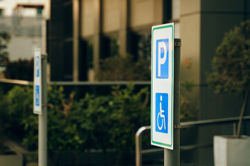 A street sign in electric blue font marks the reserved handicapped parking spot in front of the...