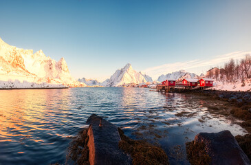 Sunrise over Reine town of fishing village on coastline and snowy mountain during winter at Lofoten...