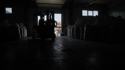 Warehousing. Forklift driver stacking big bag of raw material in warehouse. Many bags of raw materials in the warehouse