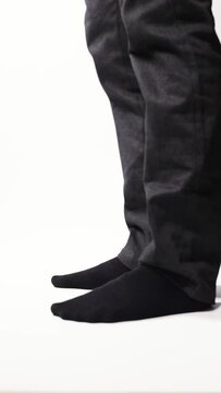 Legs of a man demonstrating black socks on a white background
