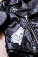 Dollars in the pocket of a leather jacket