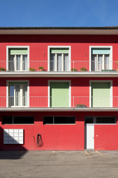 Detail of a red railing house with parking below. There is a letterbox for the entire condominium and a closed white door.