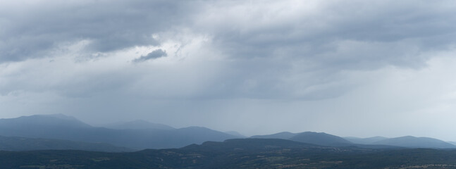 Obraz premium Mountain landscape with scattered villages during storm, dark dramatic stormy clouds