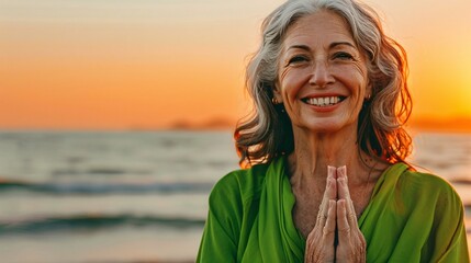 A serene senior woman smiling peacefully as she practices yoga on a serene beach at sunset - Powered by Adobe