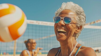 Senior woman laughing as she plays a game of beach volleyball with her friends on a sunny day - Powered by Adobe