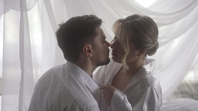 a man and a woman are kissing under a canopy on a bed