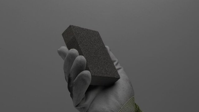 Abrasive sponge in hand on a gray background.