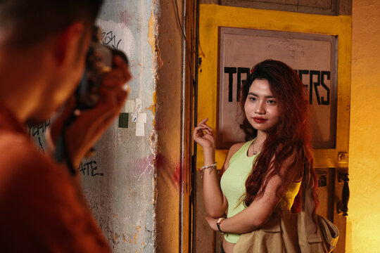 Young woman with long hair posing for photographer in doorway of old shabby building