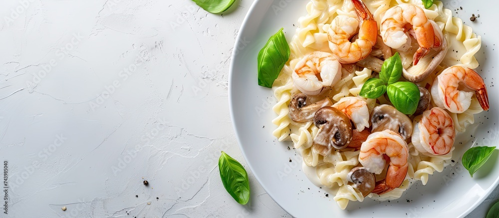 Poster spaghetti with creamy white sauce shrimps and mushrooms served on a white serving plate and garnishe