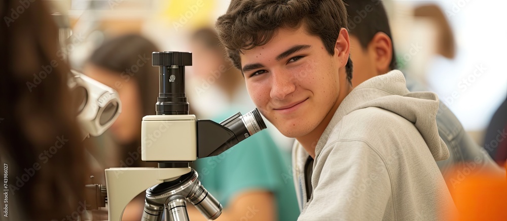 Poster close up of young woman seeing through microscope in science laboratory with other students focused 
