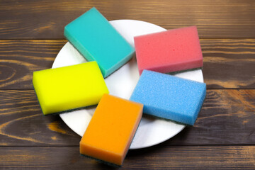 Colorful sponges for washing dishes on the white plate. Things for kitchen house cleaning.