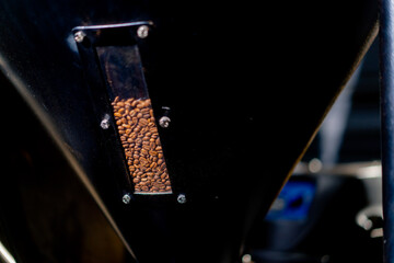close-up at a coffee factory in a roasting machine a hand opens gap and coffee pours out
