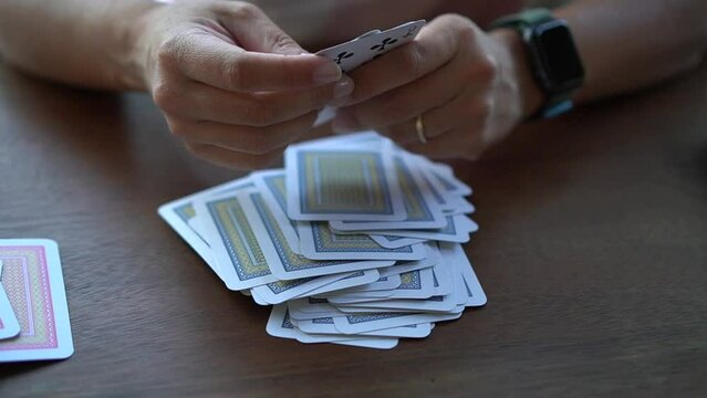 A woman is separating playing cards based on their deck colors on a wooden table