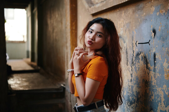 Portrait of Vietnamese girl with long hair posing at shabby wall and making kissy face