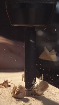 Witness the mesmerizing sight of a drill piercing through wood in stunning 4K vertical slow motion, with wood dust and chips elegantly scattering.