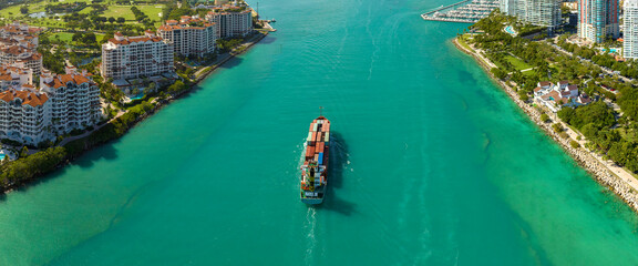 Commercial container ship entering Miami port harbor through main channel near South Beach....
