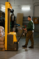 a worker at coffee factory uses a yellow forklift to lower bags of coffee
