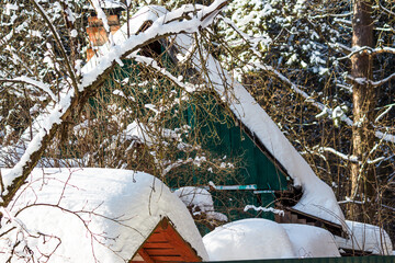 Houses and buildings on a summer cottage covered with a large layer of white snow on a winter day