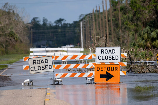 Hurricane flooded street with road closed signs blocking driving of cars. Safety of transportation during natural disaster concept