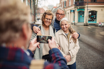Group of senior people being photographed by friend on city street