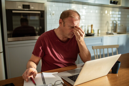 Stressed man going over bills at home