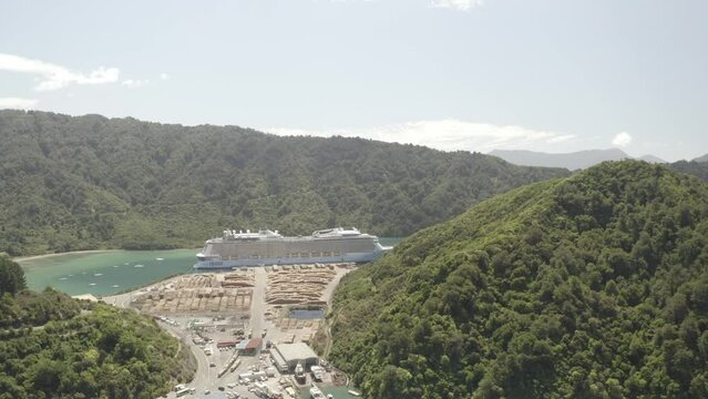 Aerial footage of a cruise ship docked between two mountains on a sunny day