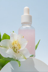 Cosmetic glass bottle with dropper on podium with alstromeria flowers. The concept of a beauty salon and natural cosmetics.