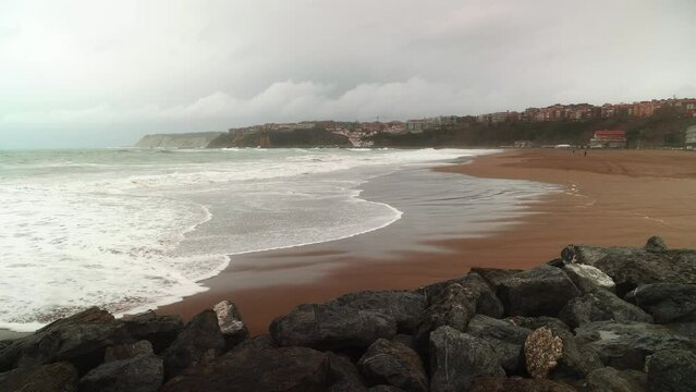 Las olas entran en una playa en un dia frio y lluvioso