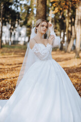 Fototapeta na wymiar Wedding portrait. Blonde bride in a lace dress with open shoulders, posing in nature. Beautiful hair and makeup. Autumn. Daylight. celebration.