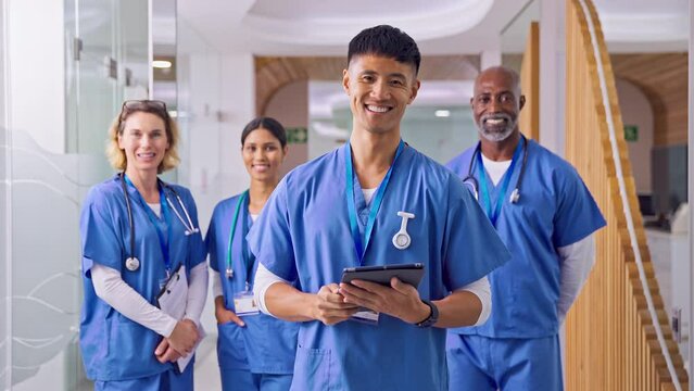 Portrait Of Smiling Multi Cultural Medical Team Wearing Scrubs In Modern Hospital 