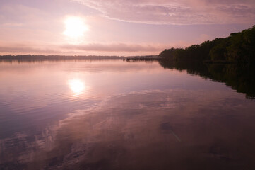 The rising sun and wispy clouds reflecting in the St. Johns River early in the morning