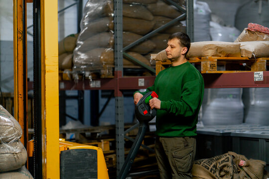 a worker at a coffee factory using forklift control panel to control the machine