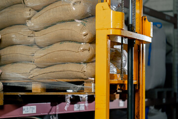 close up A worker at coffee factory uses a yellow lifting fork to lift and insert forks into pallets