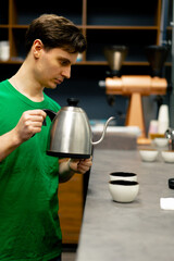 at a coffee roasting factory tester stands in the kitchen with a kettle of boiling water about to...