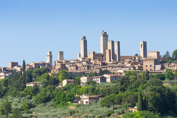 Naklejka premium San Gimignano village, Italy: green countryside, blue sky, hill panorama with town and towers