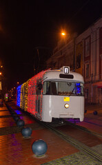 Urban tram decorated with light garlands on the evening streets in the historical part of the city....