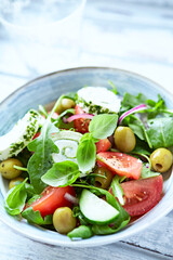 Summer Salad with Cream Cheese, green Olives, Tomatoes and fresh Basil. Bright wooden background. Close up