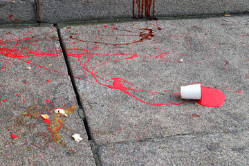 Kubek farby. Czerwona plama na chodniku. Krwawa plama.