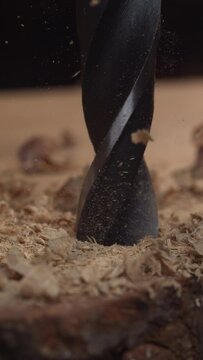 Delight in the elegance of vertical woodwork with this 4K slow-motion clip, featuring a drill making its mark on wood while wood dust and chips fly away in a mesmerizing dance.