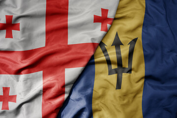 big waving national colorful flag of barbados and national flag of georgia .