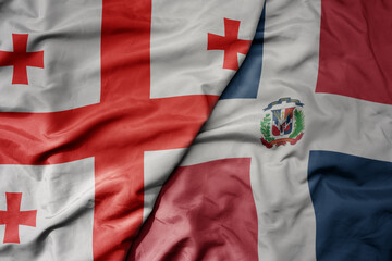 big waving national colorful flag of dominican republic and national flag of georgia .