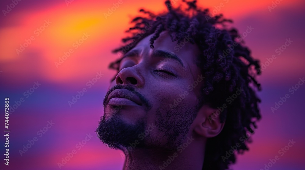 Poster a close up of a man with dreadlocks looking up at a sky with a sunset in the background and a red an